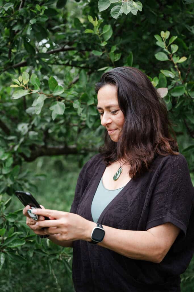 Naomi Bislip, bij een boom, kijkt naar haar mobiel